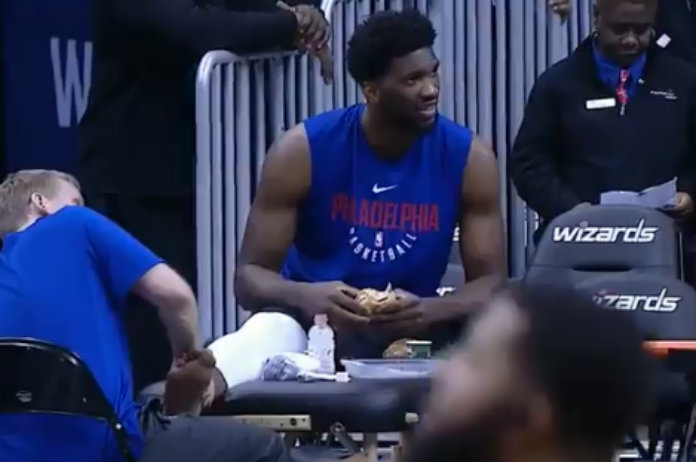 Basketbalspeler geniet net voor de match nog van hamburger