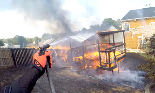 Heldhaftige motard ziet stevige brand in tuin en grijpt meteen in (video)