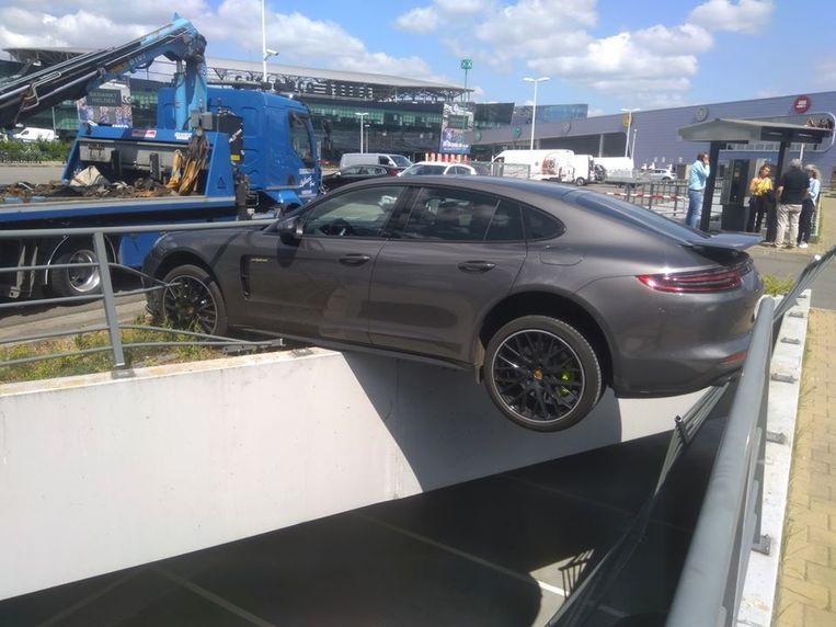 Bestuurder vergist zich van versnelling: Porsche bengelt boven parking