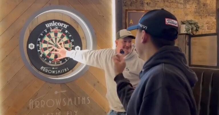 Hand op dartbord leggen tijdens pijltjepik gaat eerst goed, maar dan: “Derde keer, goede keer!” (video)